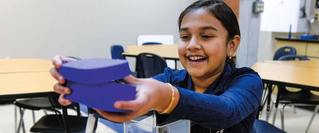 a girl smiles while holding a purple box