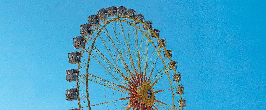 a large yellow Ferris wheel in front of a clear blue sky