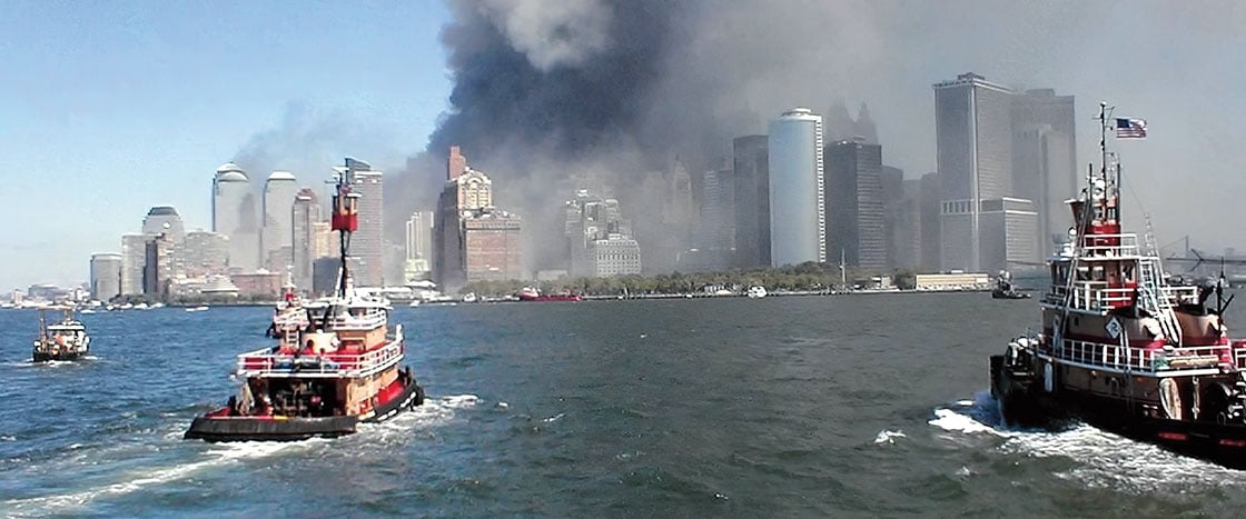 boats approaching towers that are streaming with smoke