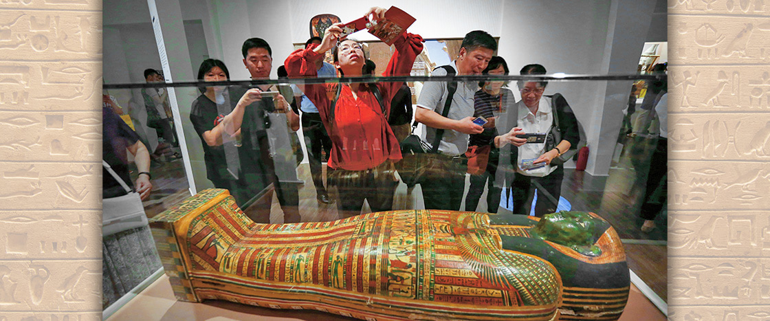 Photo of people taking photos of a mummy sarcophagus on display at a museum