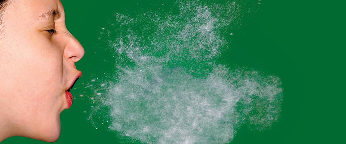 Image of a human sneezing with a puff of germs hanging in the air